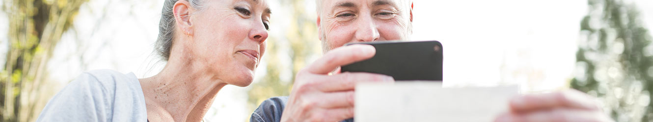 Image of a couple taking a picture of a check with their mobile device.